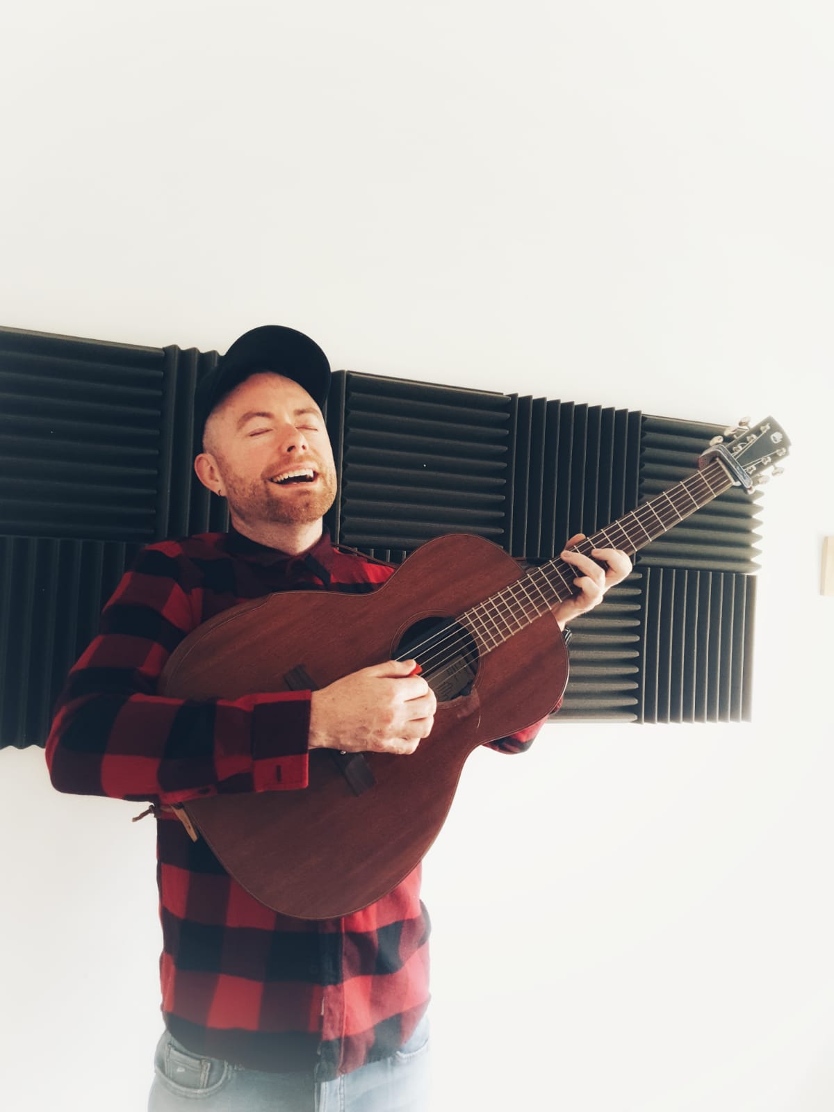 Guitar player with hat standing and playing acoustic guitar